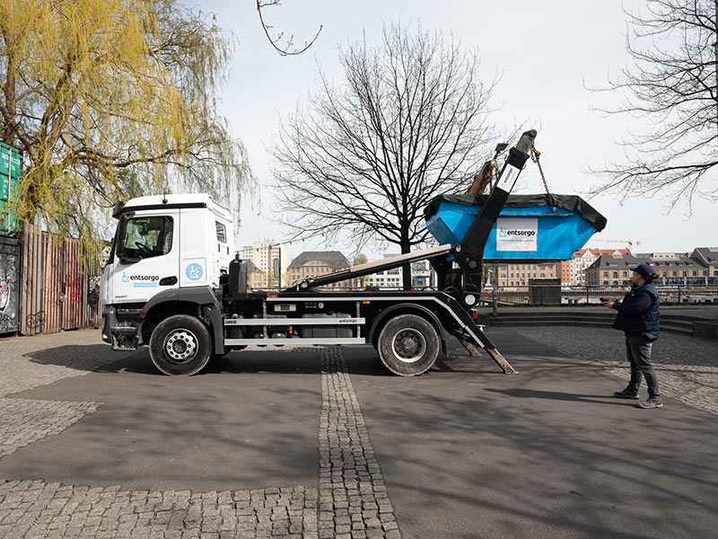 LKW mit Absetzvorrichtung stellt einen Container am Straßenrand ab.