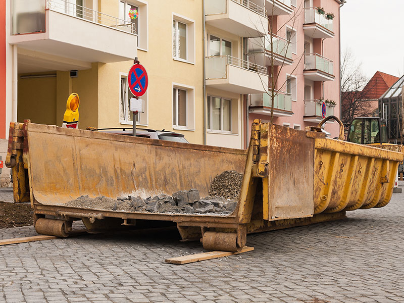 Leerer 30 Kubikmeter Container steht vor einem Wohngebäude.