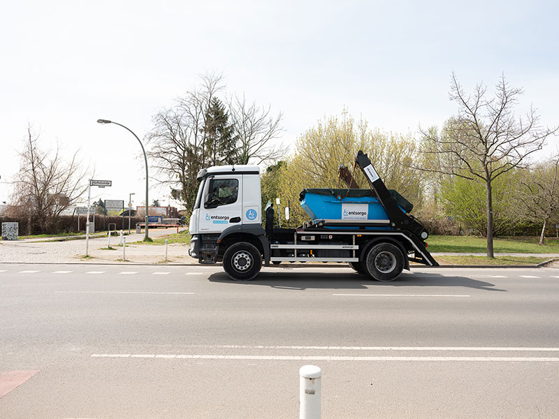 LKW mit Absetzcontainer fährt auf einer Straße.