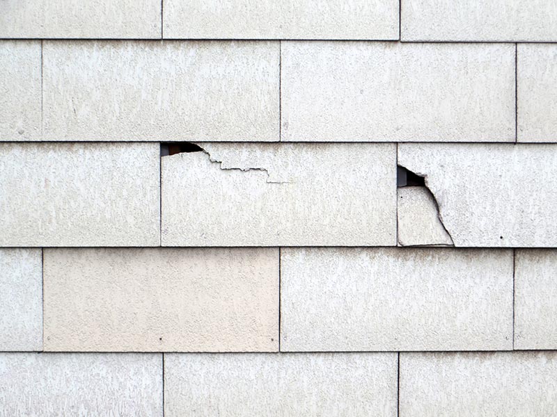 Asbestplatten an einer Fassade mit teilweise zerbrochenen Platten.