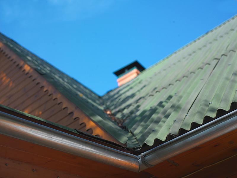 Wellplatten aus Bitumen sind auf dem Dach eines Hauses angebracht.