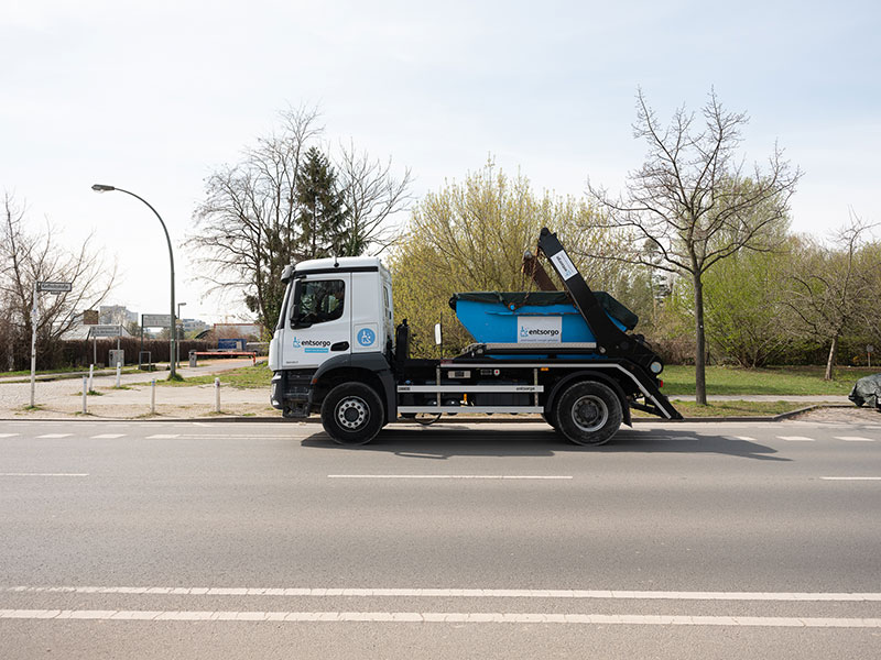 Absetzkipper mit Container auf der Ladefläche fährt auf einer Straße.