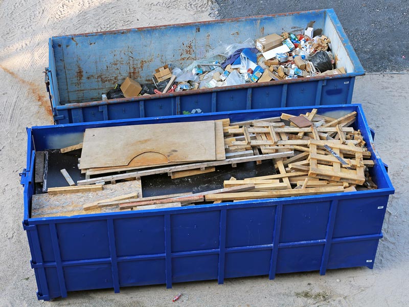 Ein mit Altholz gefüllter Container steht neben einem Container mit Baumischabfall bzw. Siedlungsabfall.