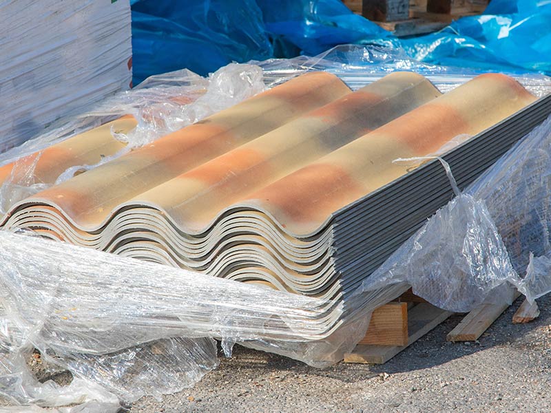 Neue Eternitplatten liegen auf einem Stapel, mit aufgerissener Folie außen herum.