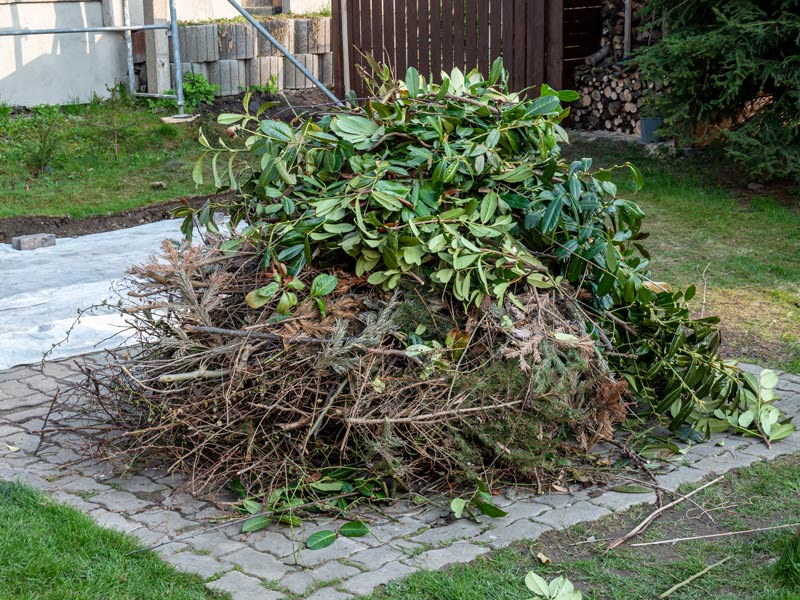 Ein großer Haufen Grünschnitt auf einer gepflasterten Stelle im Garten.