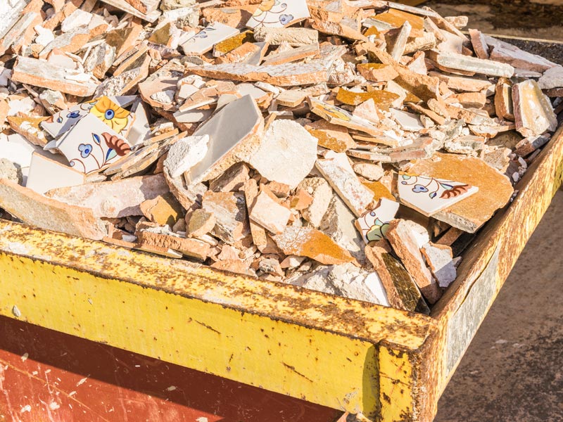 Ein Container, der mit Fliesen und anderem Bauschutt bis oben gefüllt ist.