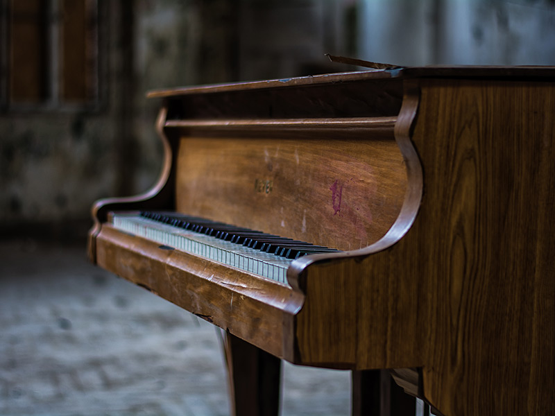 Ein altes Klavier steht in einem leeren Raum.