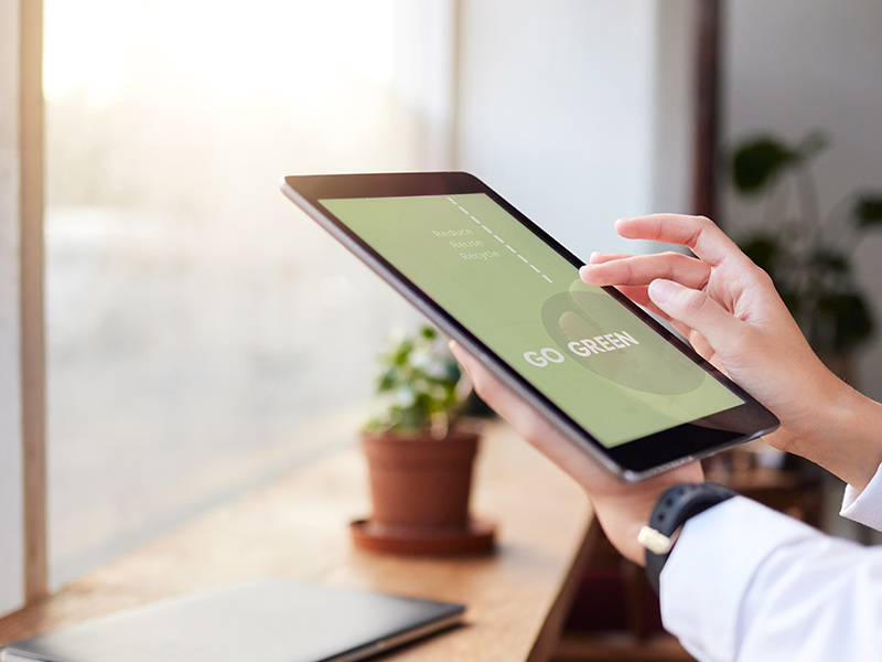 Person hält Tablet mit der Aufschrift „Go Green“ in der Hand.