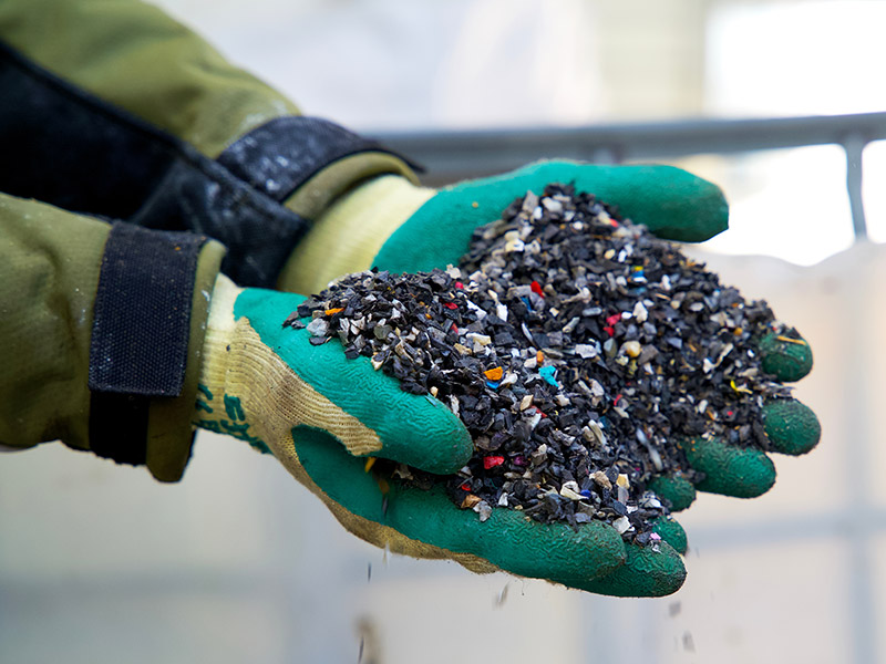 Person hält recyceltes Kunststoffgranulat in den Händen.