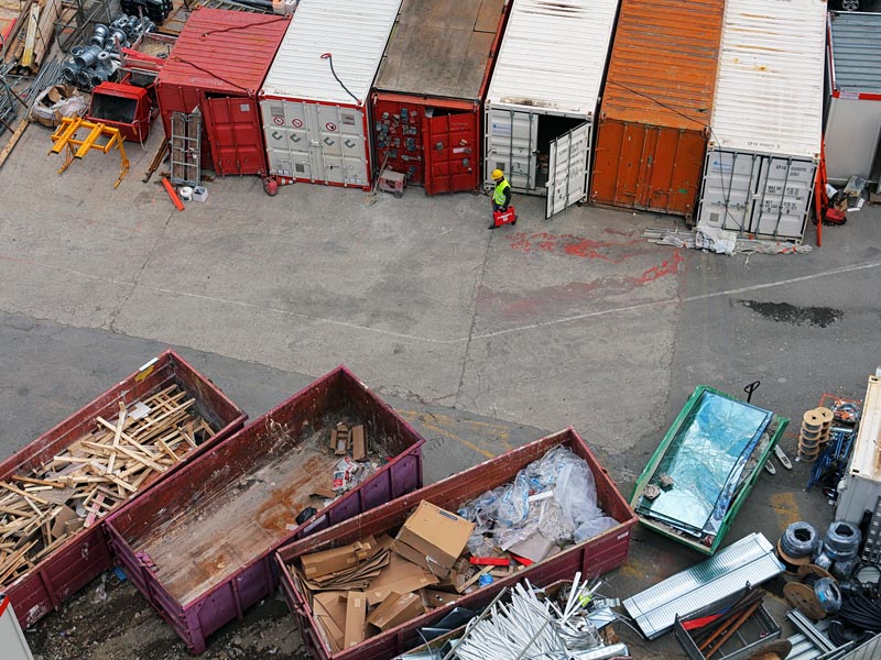 Vogelperspektive auf eine Recyclinganlage mit verschiedenen Containern für Holz, Glas und Co.