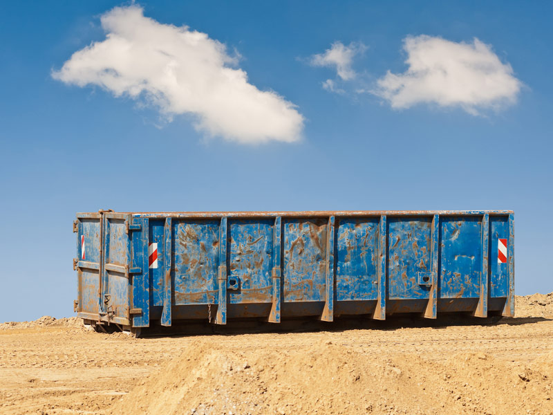 Ein großer Container steht auf einer sandigen Fläche.