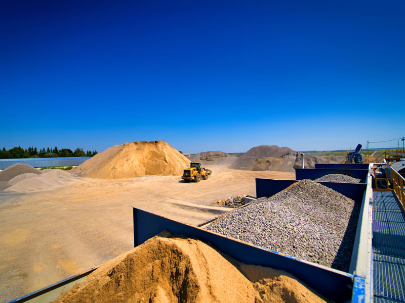 Große Container mit verschiedenen Materialien wie Sand und Kies auf einer Recyclinganlage.