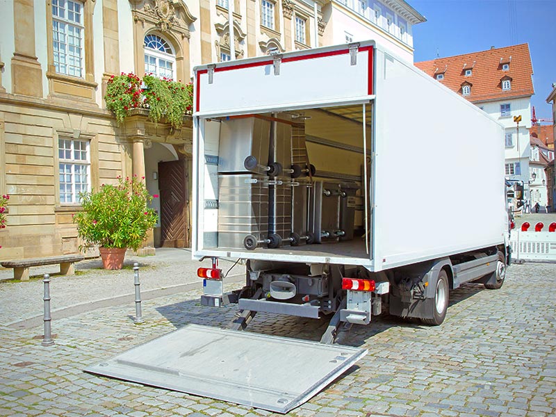 LKW steht vor einem Gebäude und ist mit mehreren Sicherheitsbehältern für Akten beladen.