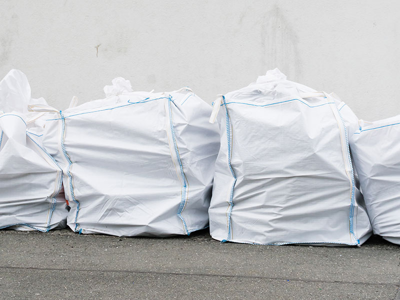 Mehrere geschlossene Big Bags mit Sondermüll stehen auf dem Boden vor einer Wand.