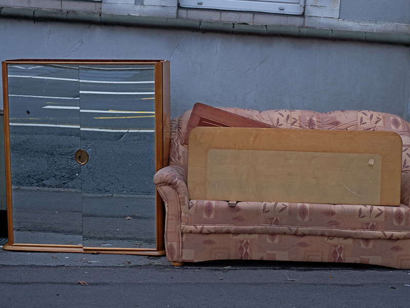 Alter Spiegelschrank steht neben einem Sofa und wartet auf die Entsorgung über die Sperrmüllabfuhr.