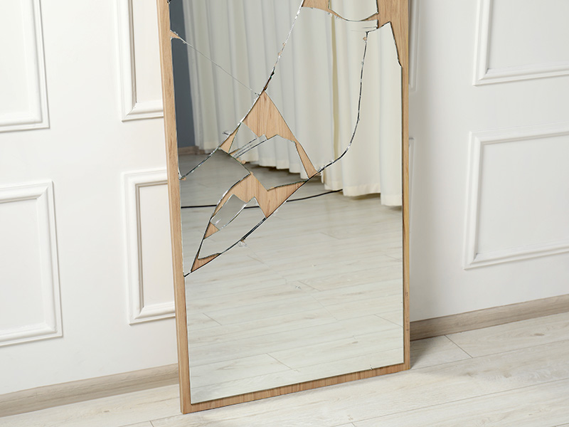 Ein zerbrochener Spiegel lehnt an einer Wand.