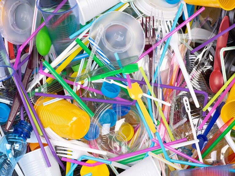 Plastikbesteck und Strohhalme liegen auf einem bunten Haufen.