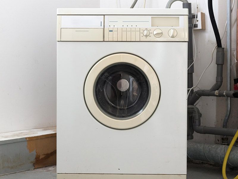 Alte Waschmaschine steht in einem Raum.